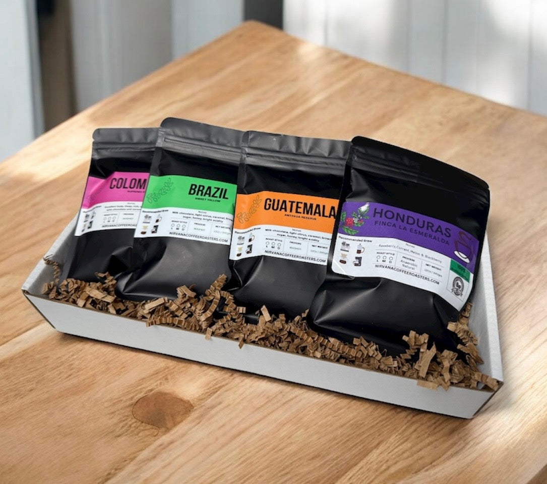 A premium coffee sample pack featuring four fresh-roasted single-origin specialty beans from the Americas: Colombia, Brazil, Honduras and Guatemala. Each bag is labeled with origin, roast date, and tasting notes. The sample pack is displayed in a kraft gift tray with shredded paper filler, highlighting the brand’s commitment to quality and freshness. Ideal for gifting or exploring regional flavor profiles at home